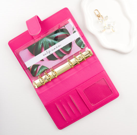 Pink binder with a leaf pattern envelope insert inside on a white background