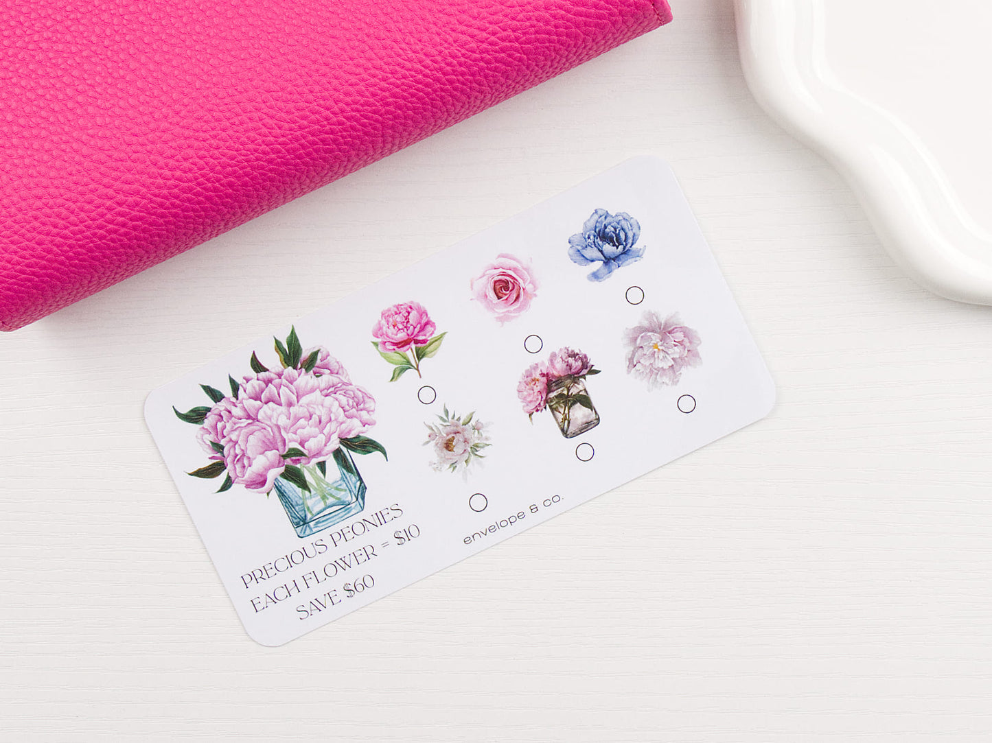 Floral-themed savings challenge on a white surface with a pink binder in the corner
