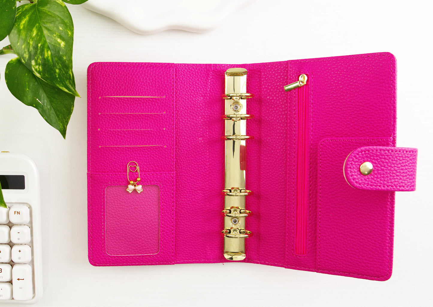 Pink binder with gold binding on a white surface