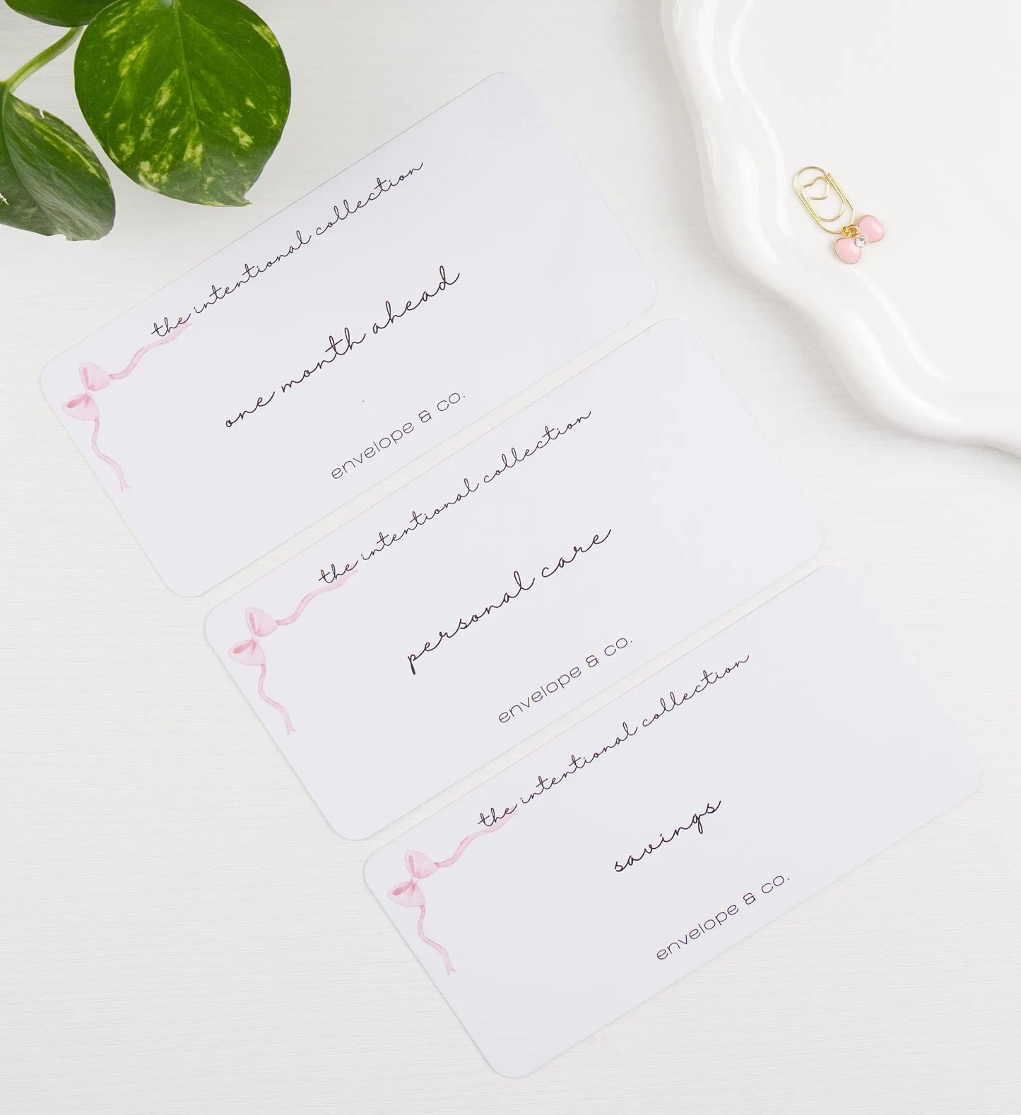 Envelope inserts with cursive text on a white surface with a plant leaf.