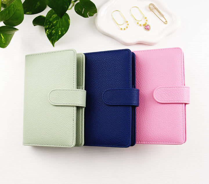 green, blue and pink binder next to charms on a tray on a white background