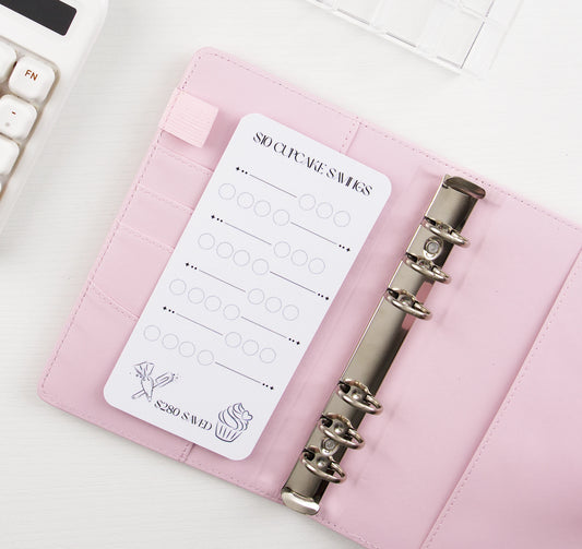 $10 Cupcake Savings challenge with rows of circles to mark off $10 deposits toward $280 goal, featuring cupcake and celebration icons, tucked into card slot of blush pink A6 binder with silver rings