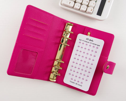 Pink binder with gold ring binder and a white savings tracker on a white background