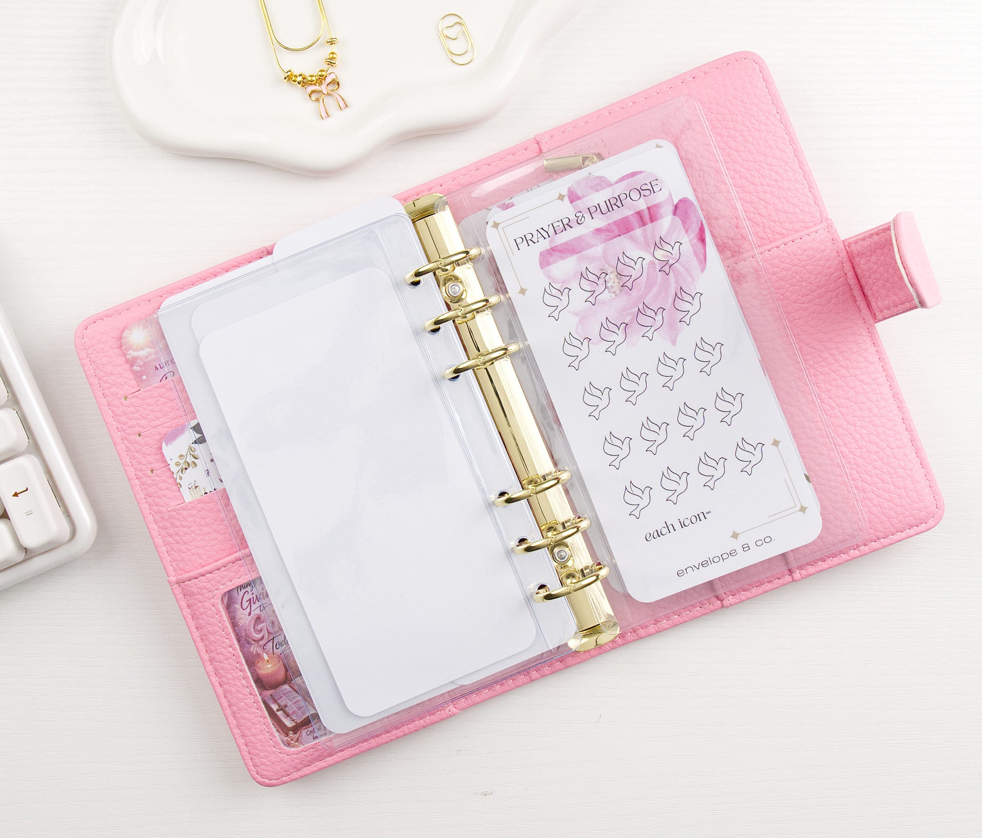 Bird-themed dashboard in a pink binder with gold ring binding on a white surface