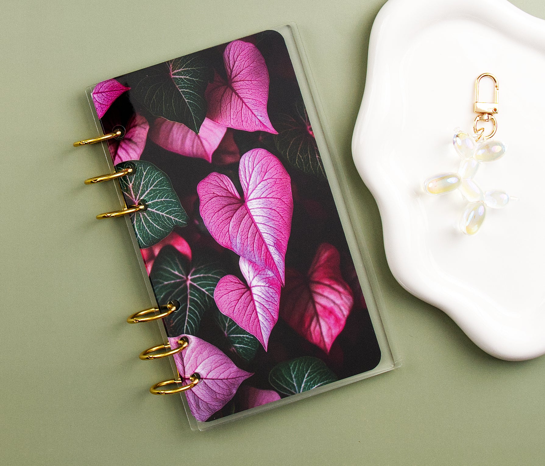 Dashboard with pink leaf design on a green surface next to a white dish and charm.