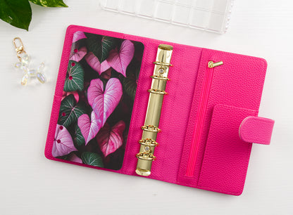 Pink binder with floral design and gold charm on a white background