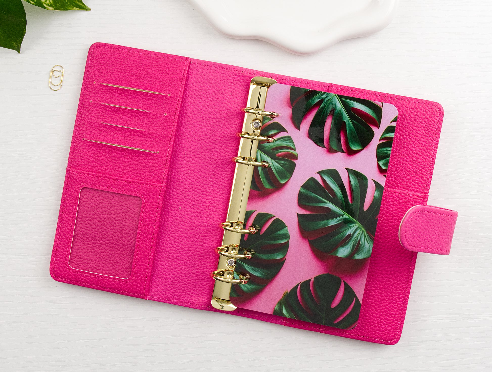 Pink binder with gold binding and tropical leaf design dashboard on a white background