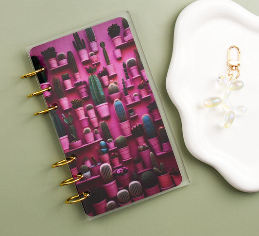 Dashboard with cactus design on a light green surface next to a white dish with a charm.