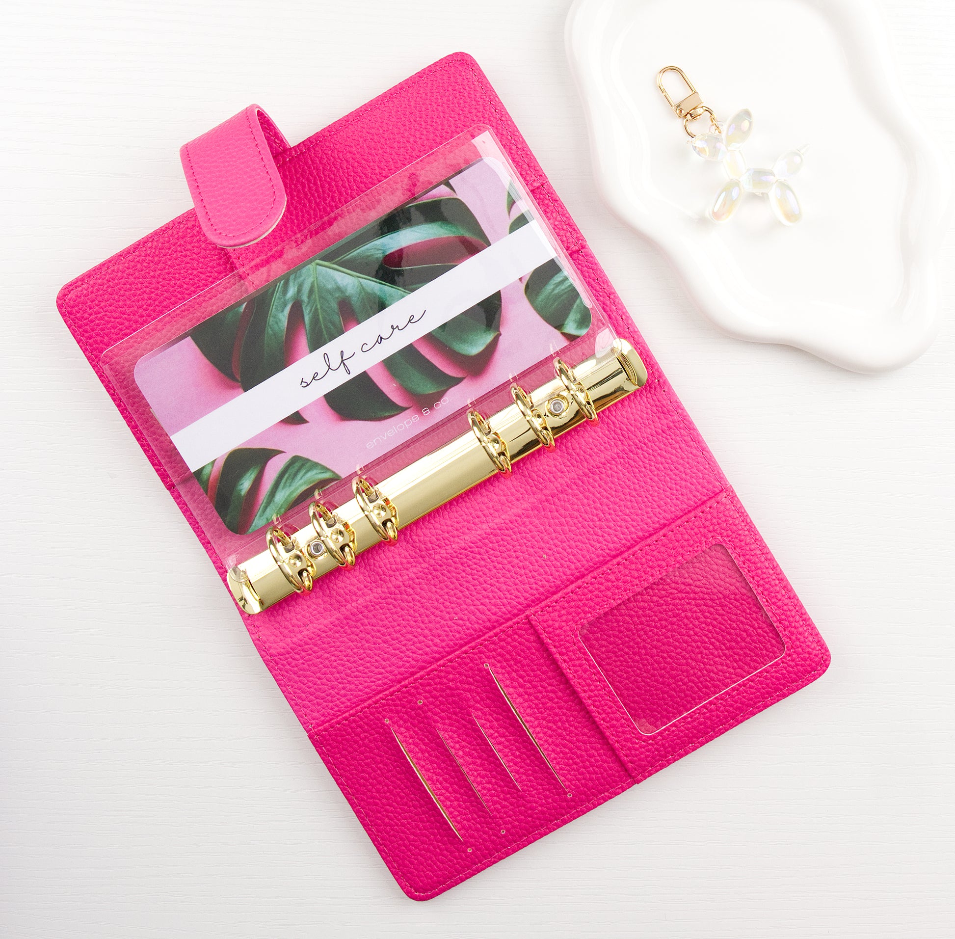 Pink binder with a leaf pattern envelope insert inside on a white background
