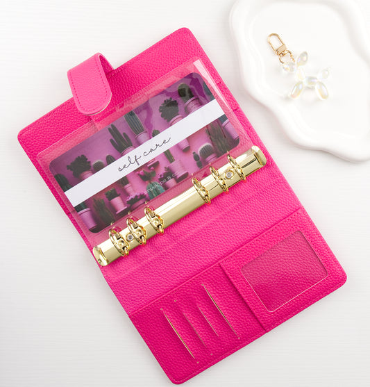 Pink binder on a white background with a cactus themed envelope insert inside 
