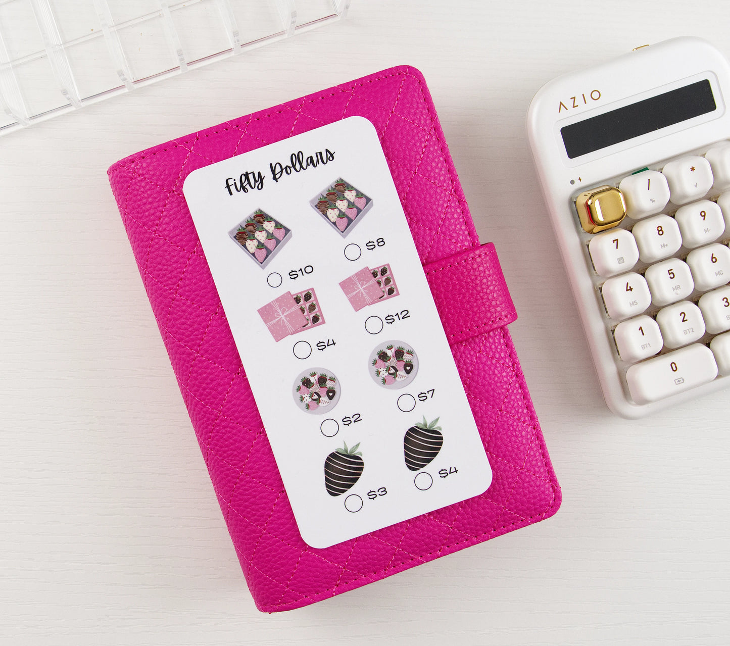 Pink binder with a savings tracker featuring on a white surface with a calculator.