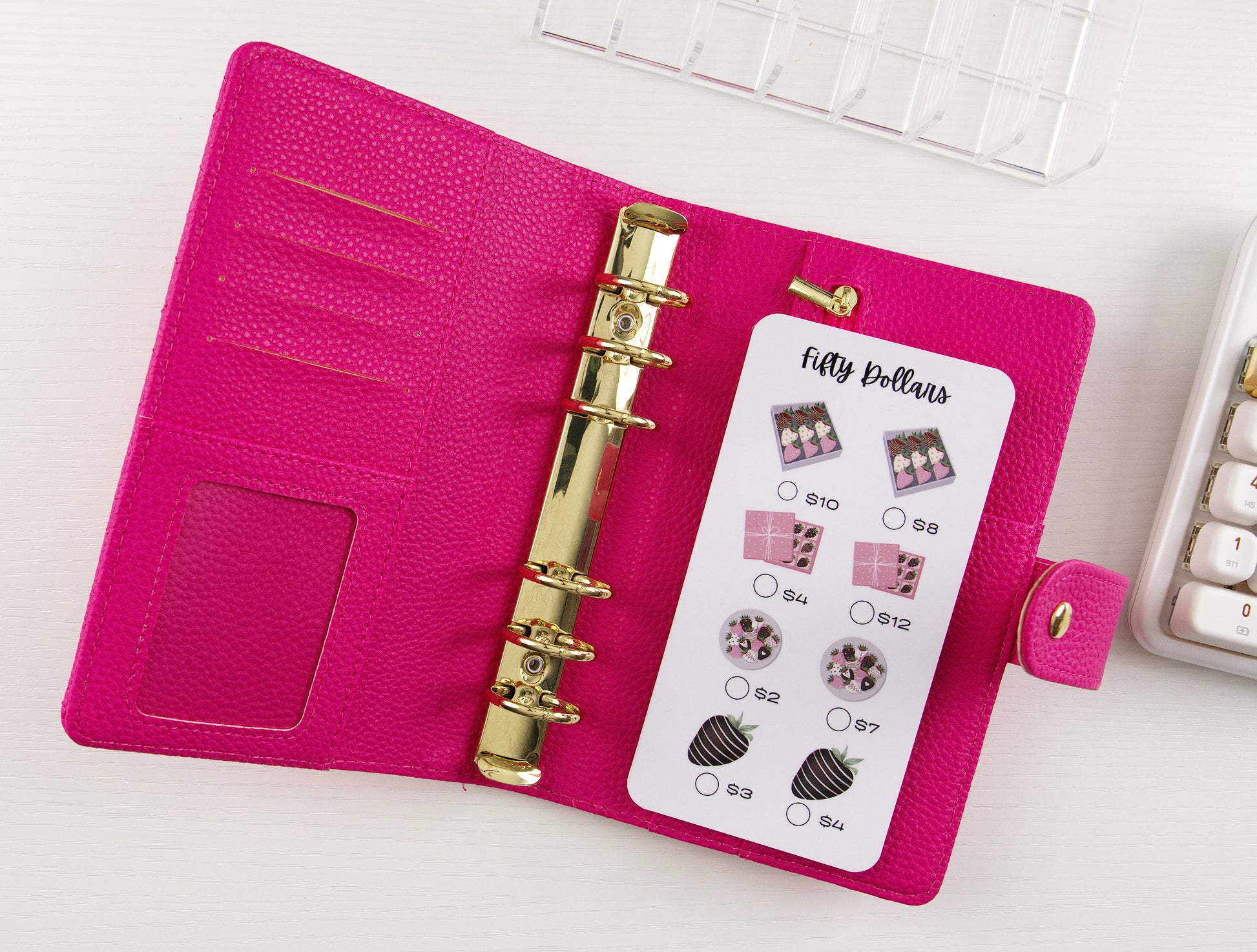 Savings tracker with chocolate treats in pink binder with gold rings on white background