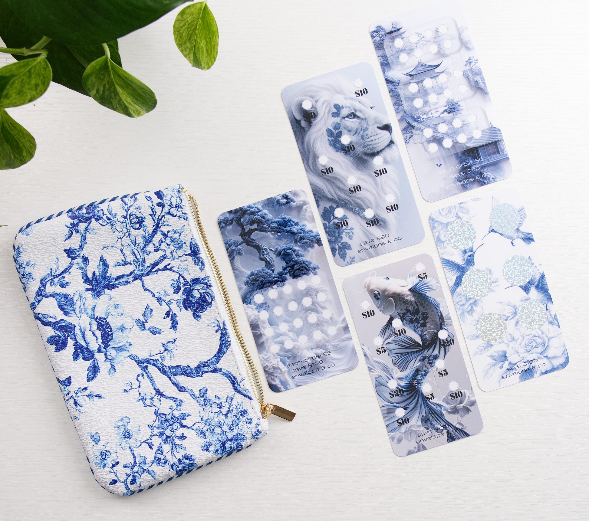 blue and white floral cash bag with blue lion and koi fish themed savings challenges a white background