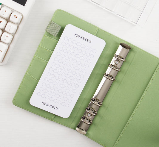 Minimalist $20 Savings tracker with circle grid design in sage green leather binder with silver rings showing $1760 savings goal