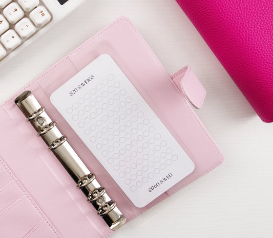 Minimalist $20 Savings tracker with circle grid design in pink leather binder with silver rings showing $1760 savings goal