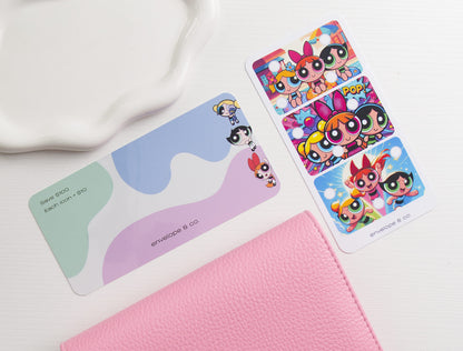 A set of colorful dashboard and savings challenge displayed on a white textured surface next to a pink textured binder and a white ceramic dish.
