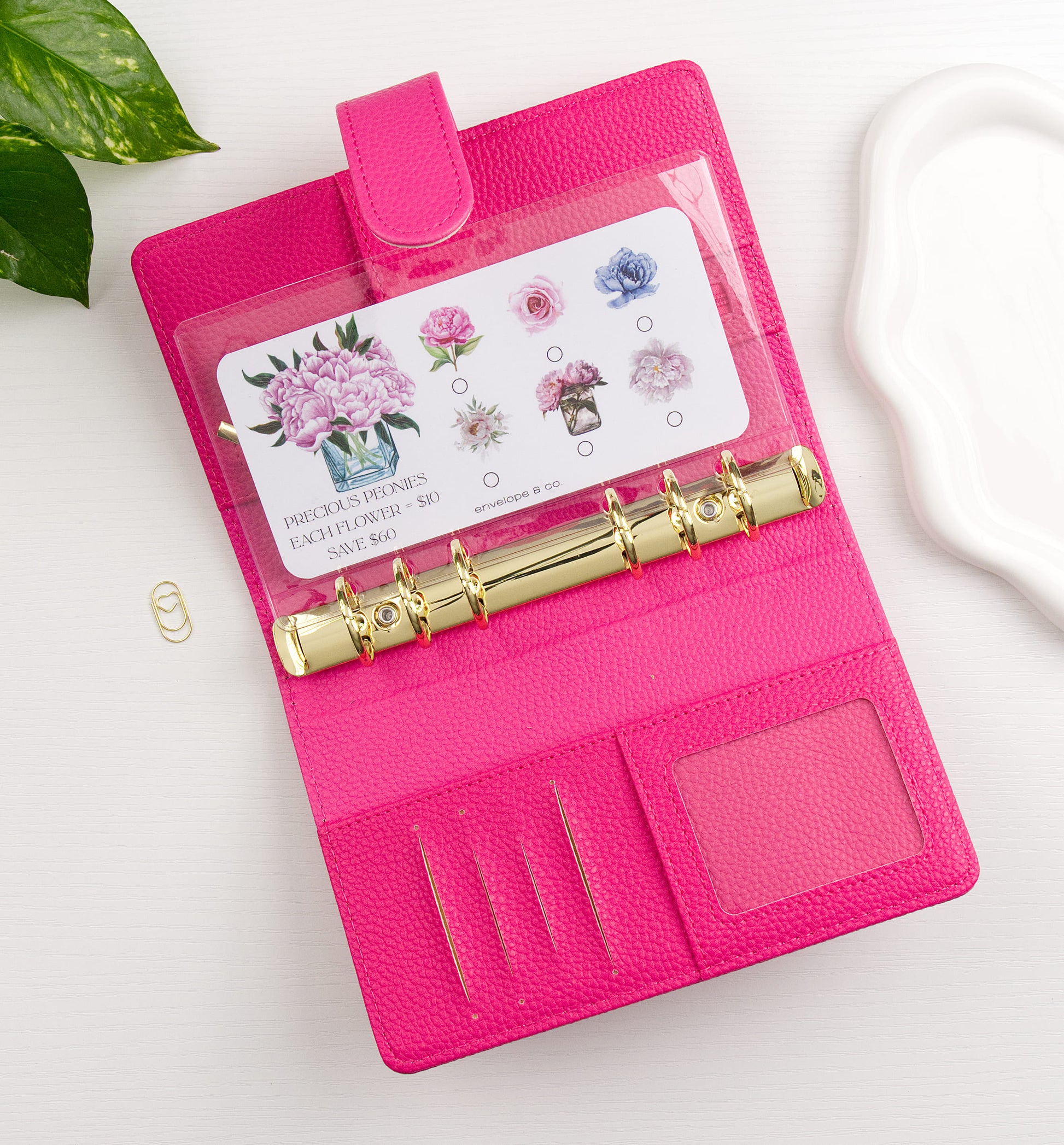 Floral savings challenge in a pink binder with gold accents on a white background