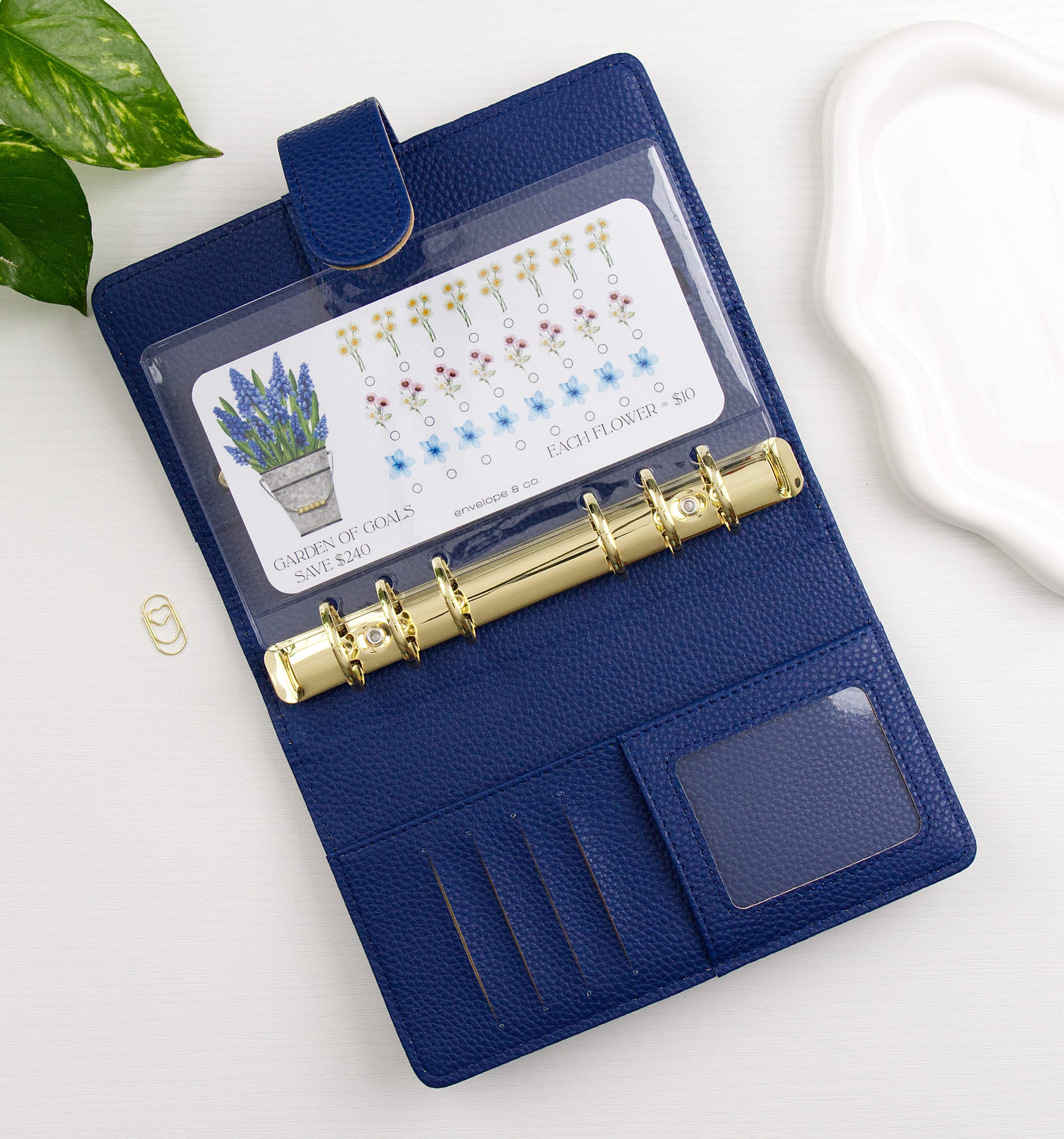 Floral themed savings challenge in blue binder on white surface