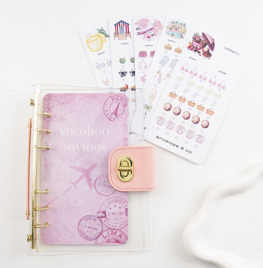 Vacation Savings Bundle with pink clear binder, passport stamp dashboard, and four customizable trackers featuring beach and travel icons