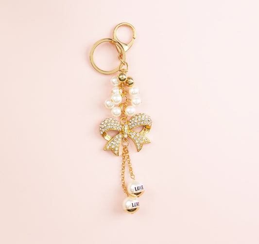 Gold bow binder chain with pearl accents on a pink background