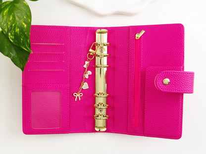 Pink binder with gold binder clip on a white background