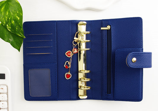 Blue binder with gold rings and heart charms on a white background