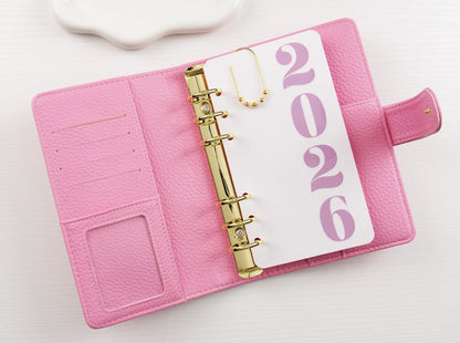 Pink binder with a '2026' page on a white background