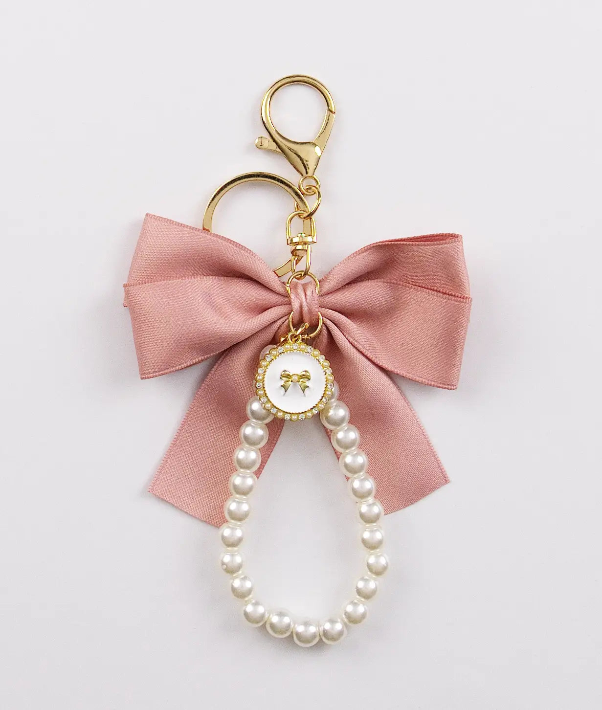 Keychain charm with pink bow and pearls on a light gray background