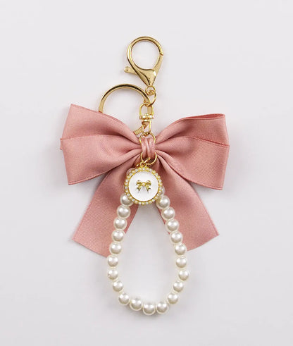 Keychain charm with pink bow and pearls on a light gray background