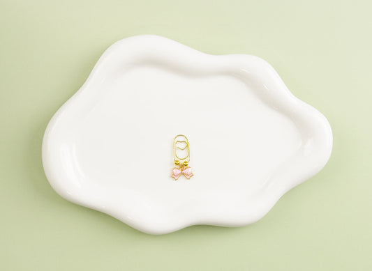 Gold and pink small heart paper clip on a white dish with a light green background