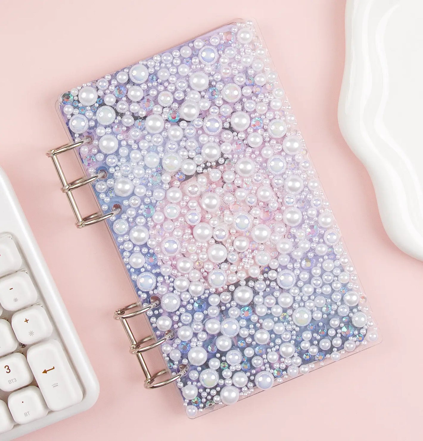 Acrylic binder with pearl embellishments on a pink surface