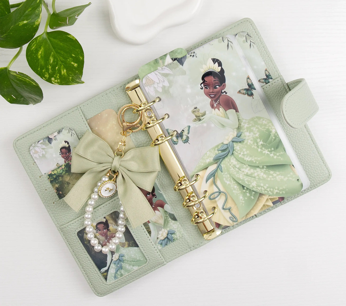 Green binder with princess design, charm, and decorative elements on a white background
