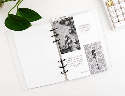 Binder with black and white design on a white surface with a plant and calculator in the background