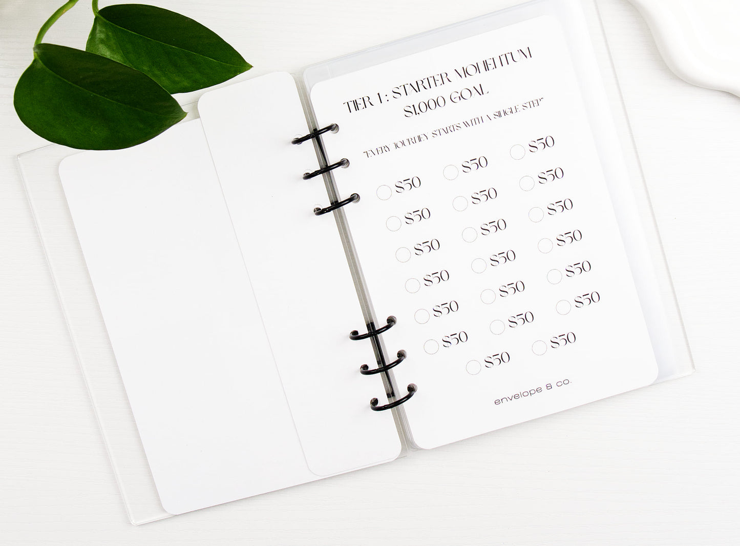 Savings challenge on a white notebook with green leaves in the corner