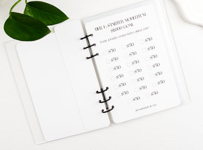 Savings challenge on a white notebook with green leaves in the corner