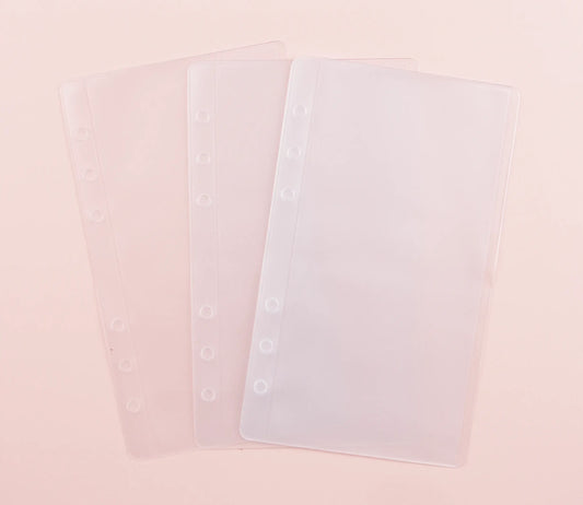 Clear plastic cash envelopes with holes punched on a pink background