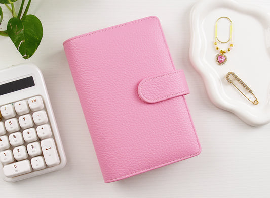 Pink binder with calculator and charms on white background