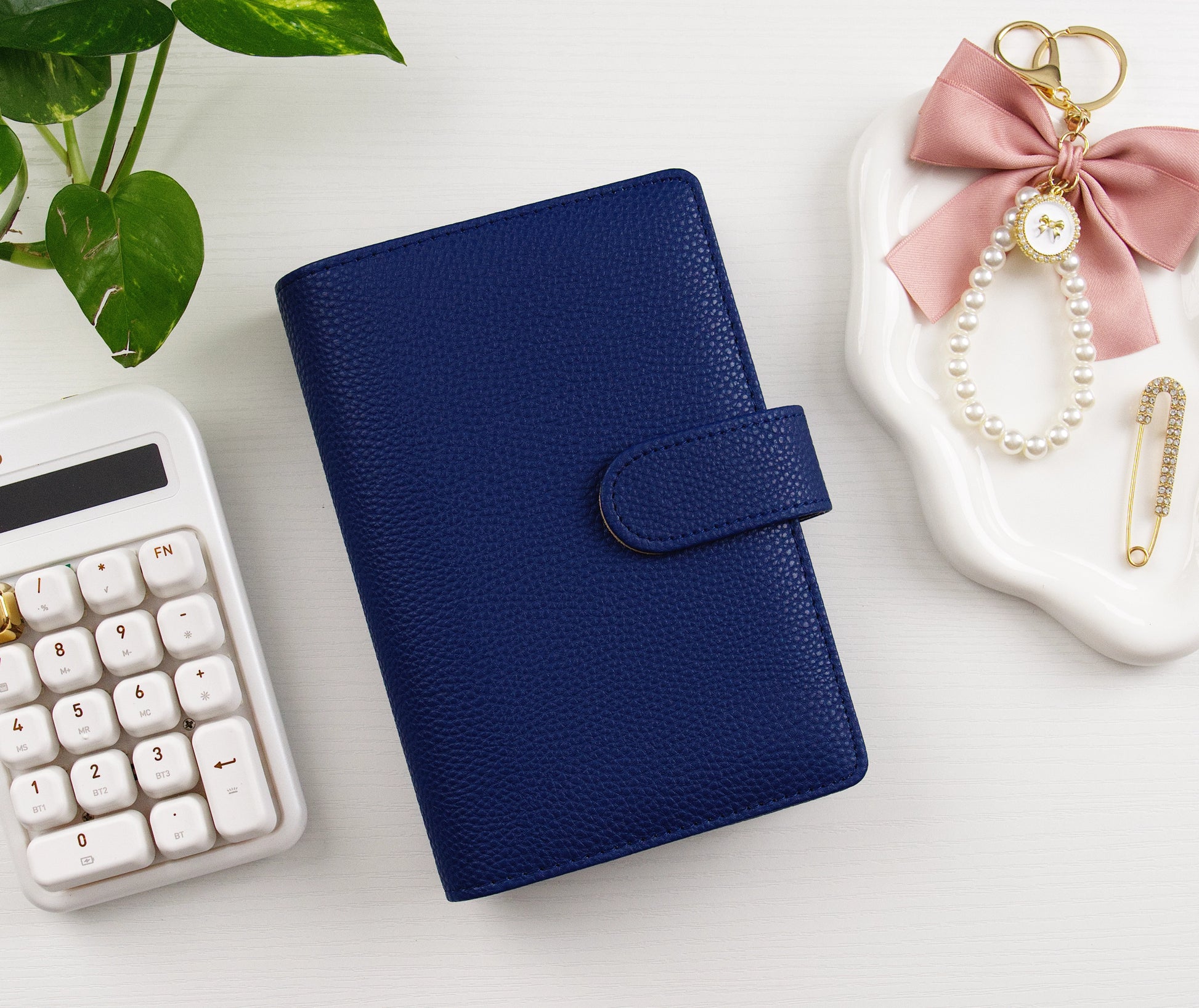 Navy binder with calculator and charms on white background