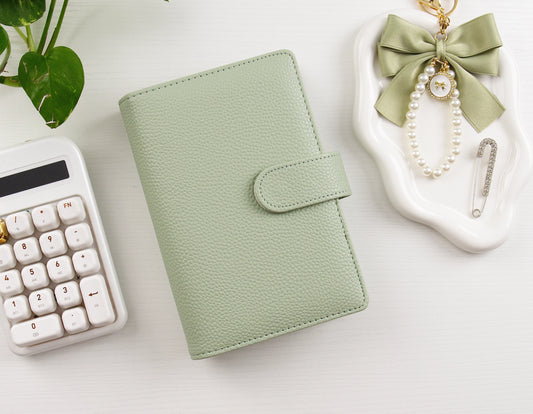 Sage green binder with a keyboard and decorative items on a light surface