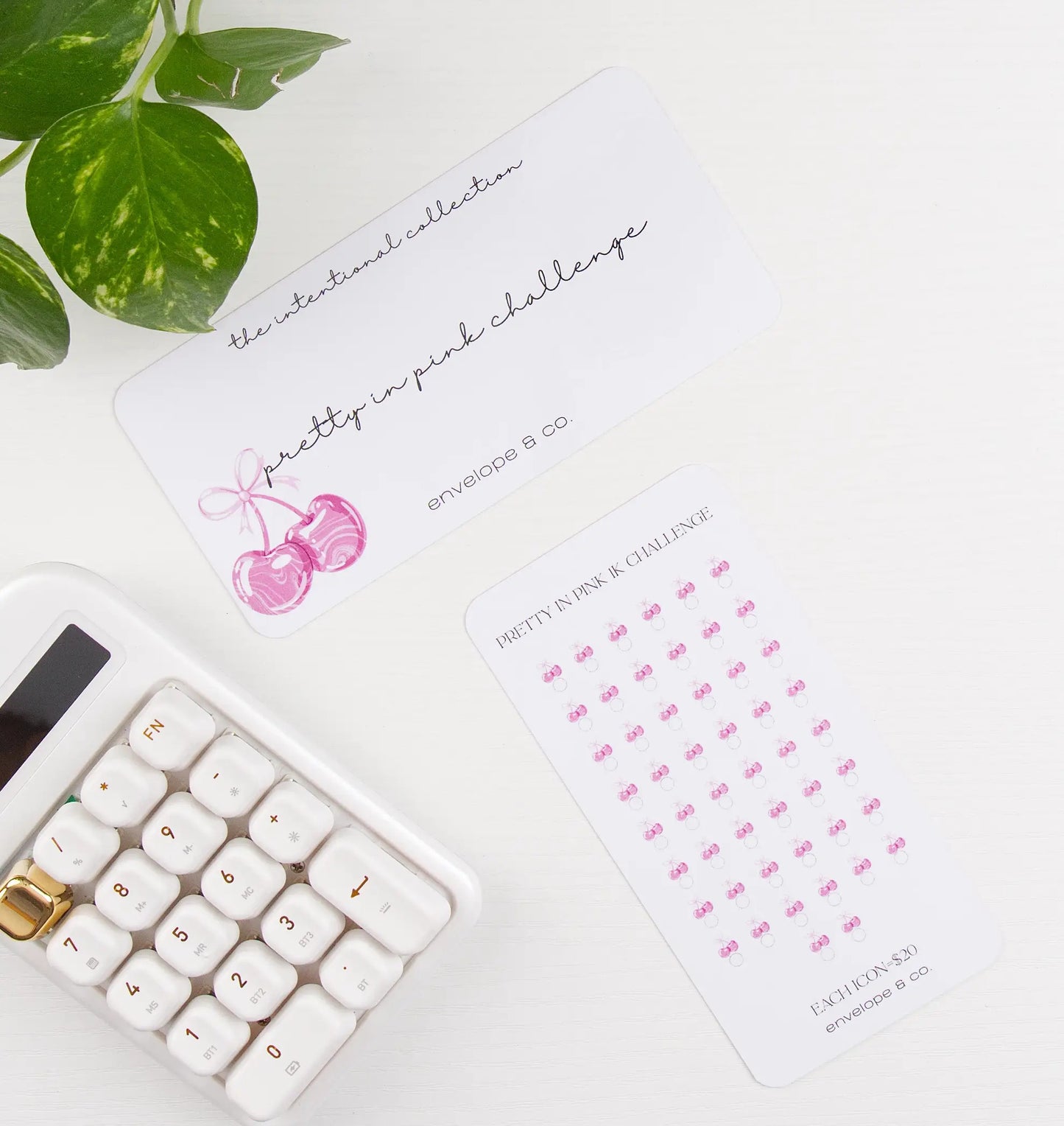 Desk setup with a calculator, plant, and cherry-themed savings bundle on a white surface