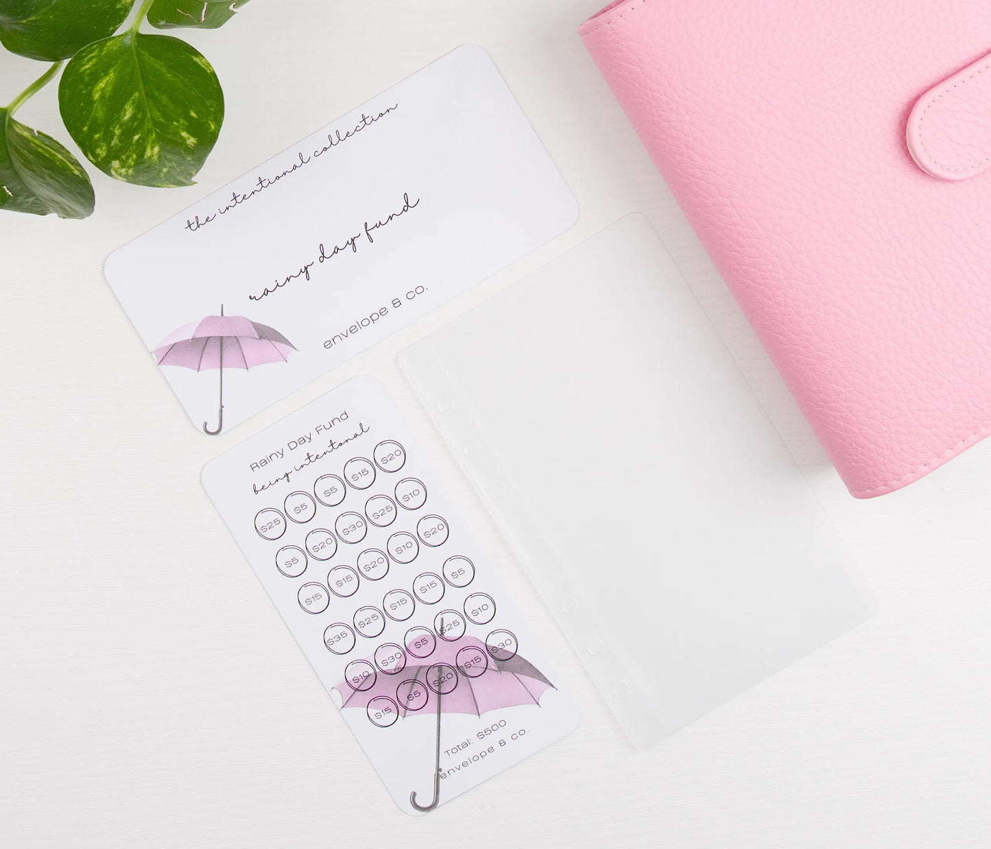 Pink binder with pink umbrella design savings bundle on a white surface.