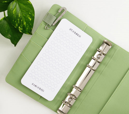 52-week savings challenge tracker with minimalist circle design in sage green vegan leather binder with silver hardware and decorative safety pin