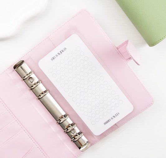Minimalist $10 Savings tracker with circle grid design in pink vegan leather binder with silver rings showing $880 savings goal