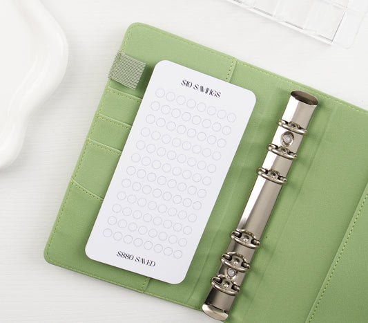 Minimalist $10 Savings tracker with circle grid design in sage green vegan leather binder with silver rings showing $880 savings goal