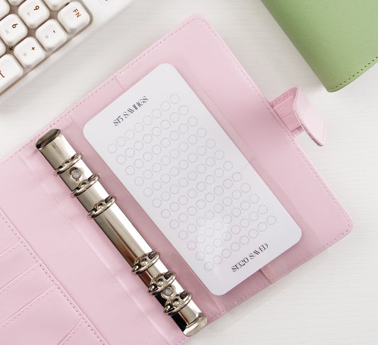 Minimalist $5 Savings tracker with circle grid design in pink leather binder with silver rings showing $220 savings goal