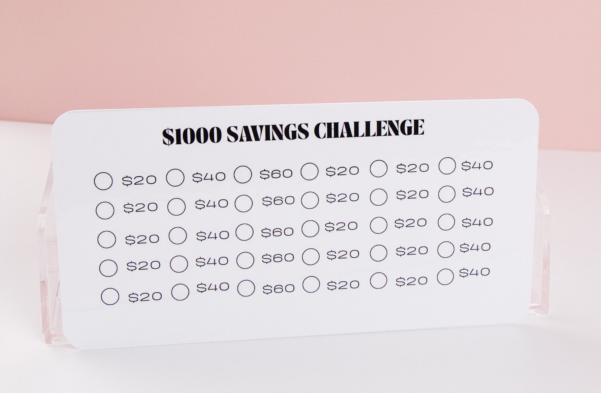 $1,000 Savings challenge tracker with various savings amounts on a pink background
