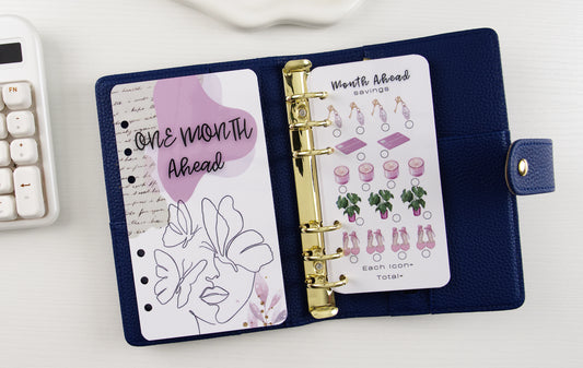 Blue binder with gold ring binding, featuring a 'One Month Ahead' dashboard on a white surface.